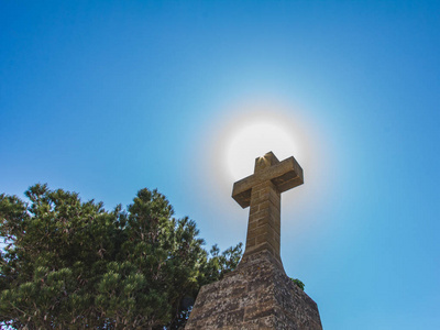 太阳升基督教符号石十字,蓝天背景,阳光从陆地观看照片