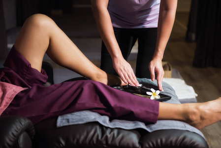 普通女性按摩器手抓香气乳液或奶油,适用于脚小腿和腿在沙发上.