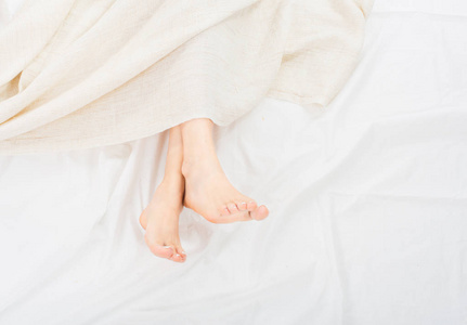 女平腿泳装女人的脚在毯子平躺着.女性美丽的脚与红色修脚在床上.