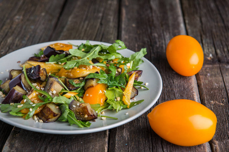 健康沙拉与烤茄子青菜，菜，菠菜，生菜，新鲜西红柿，并在旧的木制桌子上。