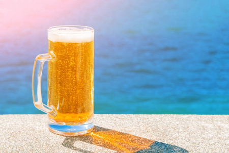 阳光下大海背景上的啤酒杯