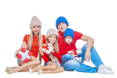家庭在圣诞节。欢快的家庭在帽子看着相机和微笑, 而孤立的白色。礼品盒在手。肖像爱家庭特写