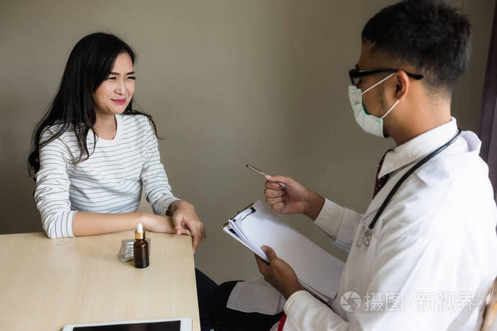 亚洲医生诊断病人的妇女与健康记录文件正在医院交谈.
