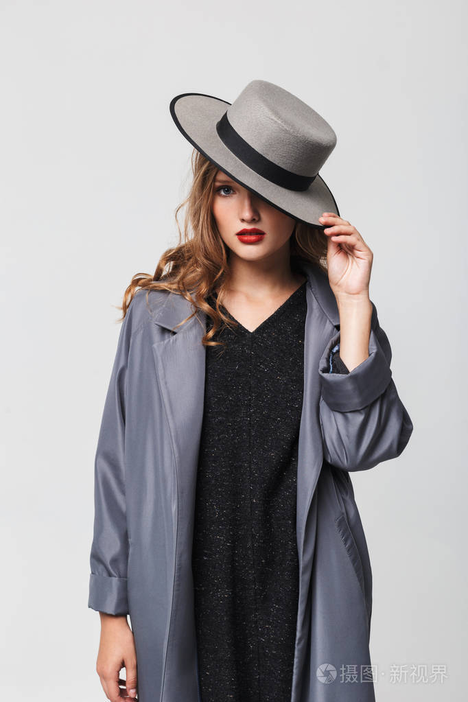 年轻漂亮的女人披着斗篷戴着帽子披着斗篷戴着斗篷在灰色背景下仔细地