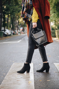 街头风格迷人的女人穿着棕色超大外套，黑色牛仔裤，脚踝靴子和鳄鱼效果手提包。 适合阳光明媚的秋天的时尚服装。