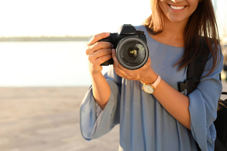 年轻的女摄影师拿着专业的相机在码头特写。 文本空间