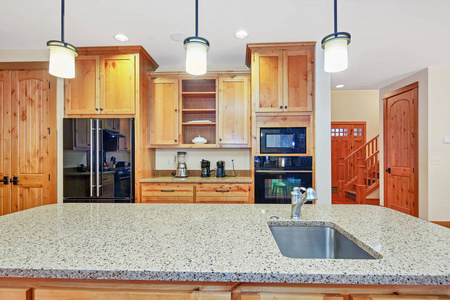 美丽的厨房与轻木橱柜花岗岩台面和黑色电器。