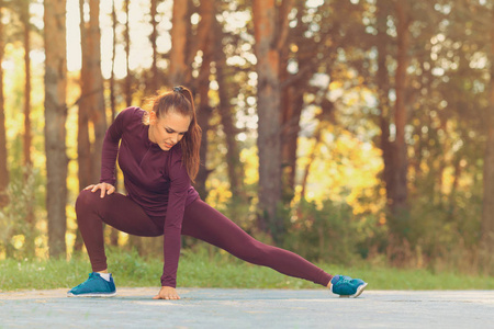年轻运动的女人跑步前伸展腿。 健身运动和减肥概念