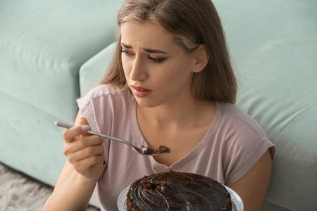 孤独抑郁的女人在家吃巧克力蛋糕