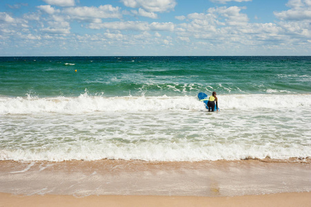夏天女孩学会在海里骑冲浪板。 在一个美丽的地方在海浪上骑冲浪板。 海滩上的冲浪学校。