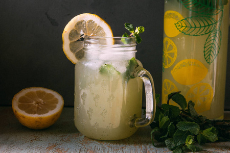 新鲜的冷的和明亮的柠檬水，在桌子上的罐子里放着薄荷和混凝土背景
