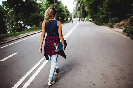 背着滑板走在路上的金发女人的后景