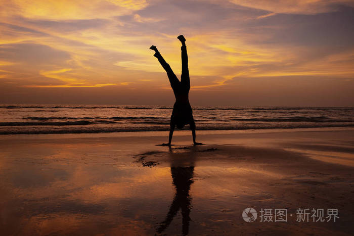 日落时分人们在海滩上倒立
