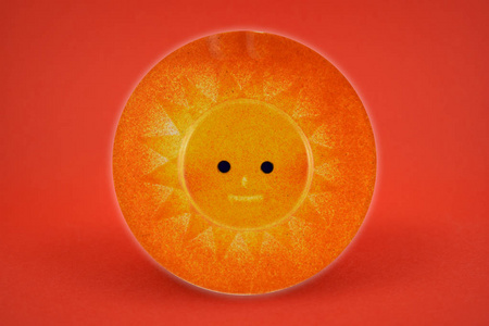 橙阳装饰股票形象..在红色背景上隔离的陶瓷太阳。圆圆的太阳装饰品。快乐太阳股票图片