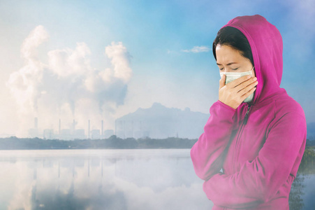 防止空气污染打喷嚏的女人穿着粉红色的冬衣,脸上戴着口罩,以防止空气