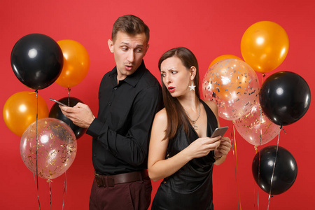 夫妻俩背靠背地在手机上传递信息，庆祝生日，节日聚会被隔离在红色背景气球上。 圣瓦伦丁国际妇女节2019年新年快乐概念。 嘲弄