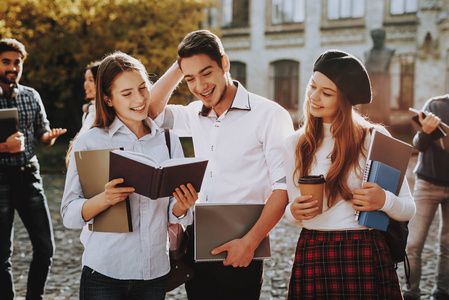 晴天。 学生。 两个女孩和男孩。 一起。 庭院。 拿着书。 站在大学里。 好心情。 情报。 站在一起。 在外面。 朋友。 快乐。