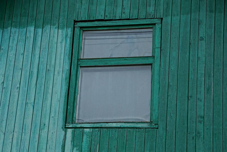 一扇绿色木墙上的旧窗户