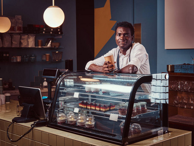 非洲咖啡师在下班后悠闲地喝咖啡, 同时靠在咖啡厅柜台上
