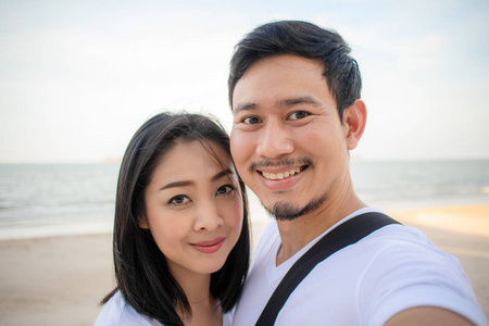 浪漫的亚洲夫妇在海滩上自拍。