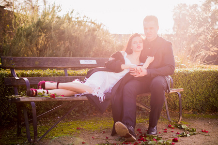 情侣躺在照片上恋爱中的情侣,一个女人躺在长凳上,一个男人坐在长凳上