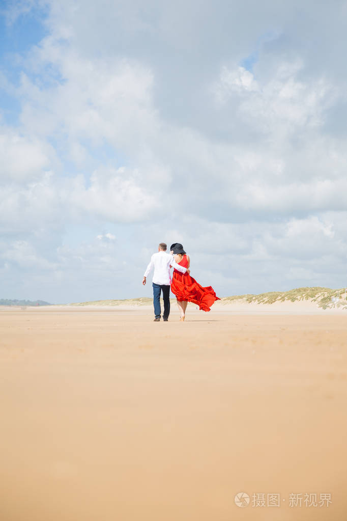 一对浪漫的年轻夫妇在海滩上拥抱的背影