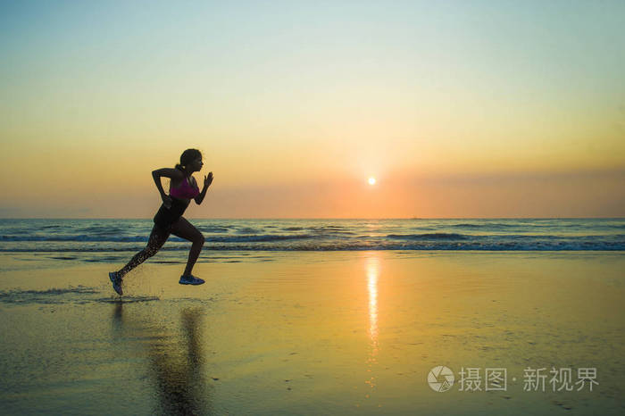 年轻,快乐和有吸引力的非裔美国跑步妇女的剪影,她在美丽的海滩慢跑中