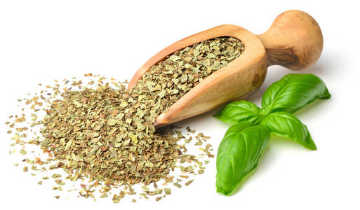 干燥的草本罗勒叶在木勺中分离在白色背景上照片