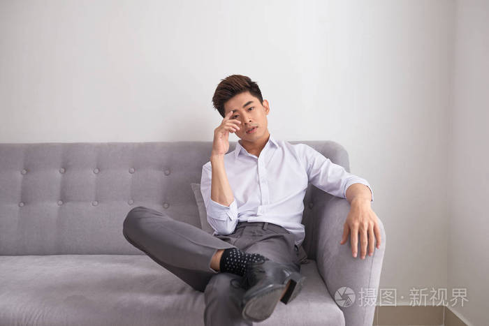 快乐英俊的亚洲男人在家里的沙发上放松客厅