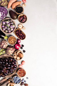 各种紫色原料的生有机茄子，洋蓟，土豆，洋葱，浆果，胡萝卜，布鲁塞尔，芽，葡萄，灰色混凝土背景。 太空食物架的俯视图