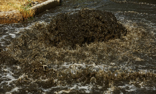 事故污水处理系统。 水从下水道流过道路。 下水道里的事故。 突破污水系统。 水从沙井里流出。 在道路上的污水井上浇制供水系统