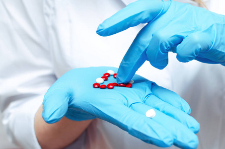 红白片药片在医生手上穿着蓝色的医疗手套。