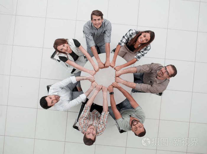 微笑的商业团队折叠他们的手形成一个圆圈