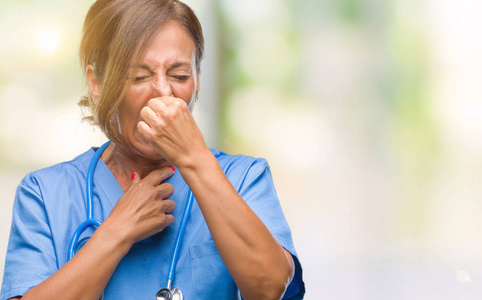中年高级护士医生女人隔着孤立的背景闻着一些臭而恶心的东西，难以忍受的气味，用手指在鼻子上屏住呼吸。坏气味的概念。