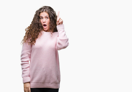 美丽的黑发卷发年轻女孩穿着粉红色的冬季毛衣，在孤立的背景上指点着手指，成功的想法。离开而快乐。一号。