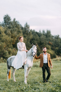 美式婚礼，在农场和马一起举行。日落时分，和朋友一起骑马在田野里散步。现代夫妇和仪式的想法。