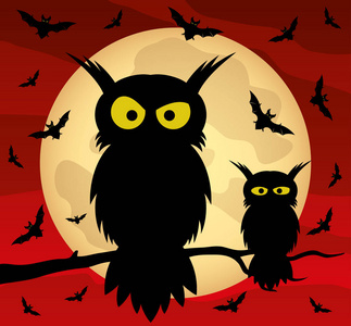 树枝上的两只猫头鹰和月亮背景上的蝙蝠.照片