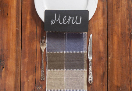 餐厅菜单设计。 餐厅菜单，空盘和餐具在木制背景与彩色餐巾纸。 顶部视图，文本复制空间