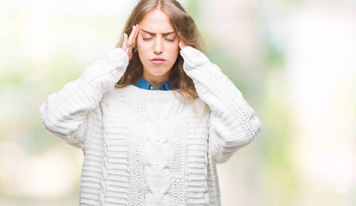 美丽的年轻金发女人穿着冬季毛衣，在孤立的背景上，手在头上疼痛，因为压力。 偏头痛。