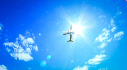天空蓝色的浅白云穿透了被太阳照亮的飞机的优雅轮廓。