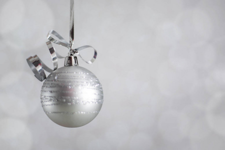 银色圣诞新年球与卷曲彩带蝴蝶结在闪闪发光的bokeh灯背景与复制空间的文本