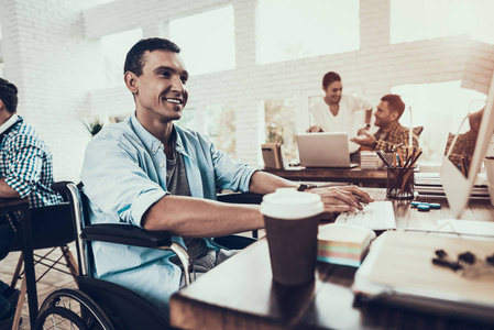 坐轮椅的人在办公室里用电脑工作. 残疾青年. 坐轮椅的人.