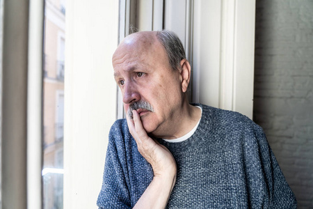 鳏夫年老的老人看着整个窗户,感到困惑和沮丧,独自在家,在老年退休