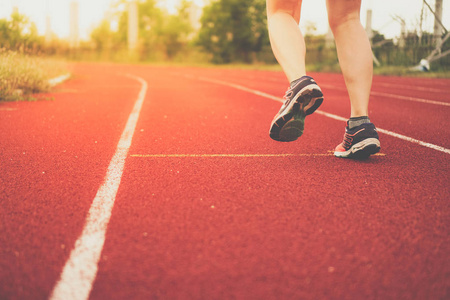 女人穿着运动鞋在球场背景下跑步. 健康锻炼生活方式的概念.照片