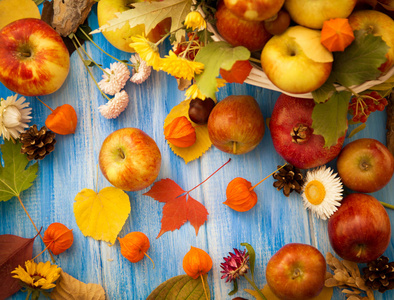秋天明亮的背景。 蓝色木制背景上的花朵叶子和水果。 秋季假期和感恩节的背景。