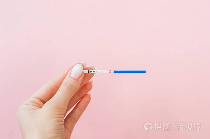 怀孕测试在女性手上粉红色背景阳性结果