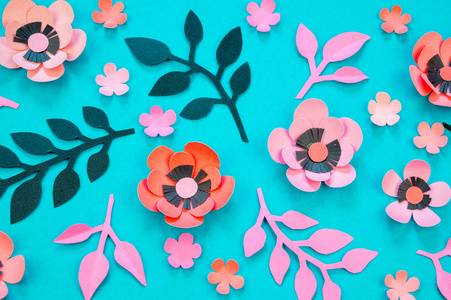 在绿松石背景上用纸做的花和叶子。 手工最喜欢的爱好。 粉红色黑色和蓝色。