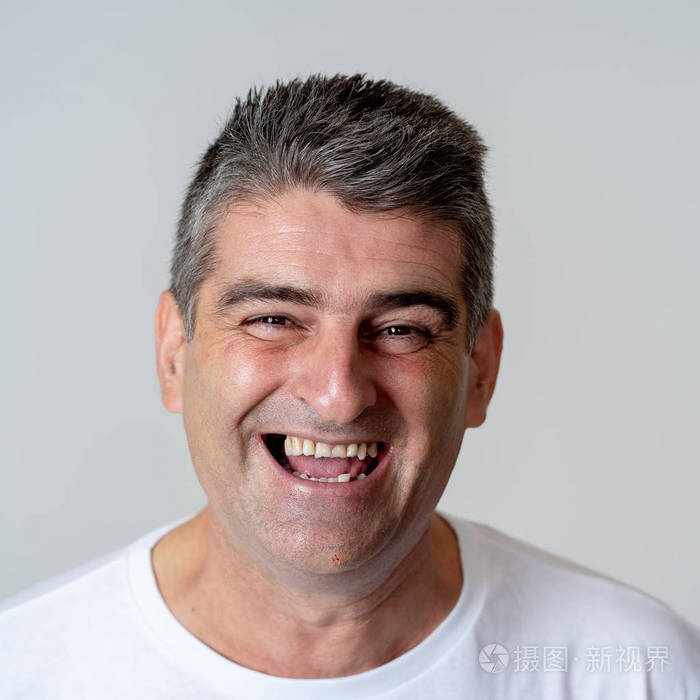 特写一个有魅力的中年男人的肖像他玩得很开心快乐微笑笑着看着镜头在