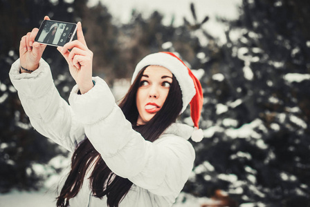 拍自拍的女孩。 圣诞女孩户外自我肖像。 穿着冬装戴着克劳斯帽子戴在雪地上的女人