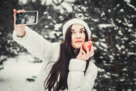 拍自拍的女孩。 圣诞女孩户外自我肖像。 穿着冬装戴着克劳斯帽子戴在雪地上的女人